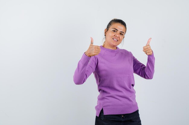 Jeune femme montrant les pouces vers le haut et l'air heureux