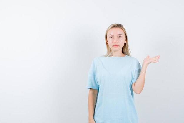 Jeune femme montrant quelque chose en t-shirt et semblant confiante