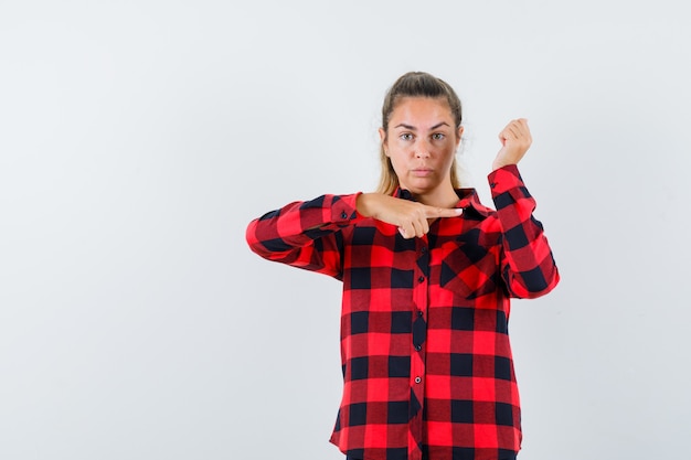 Jeune femme montrant sa manche en chemise à carreaux et à la confiance