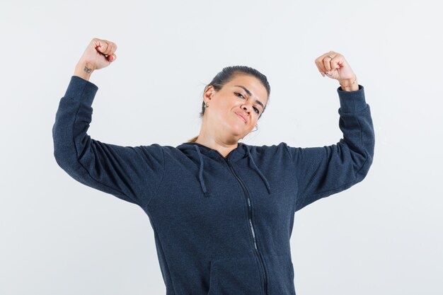 Jeune femme montrant ses muscles du bras en veste et à la recherche de souplesse. vue de face.