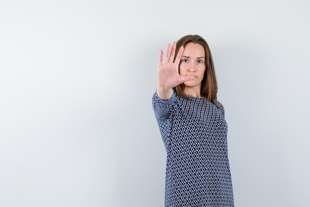 Jeune femme montrant un signe de la main d'arrêt sur fond blanc