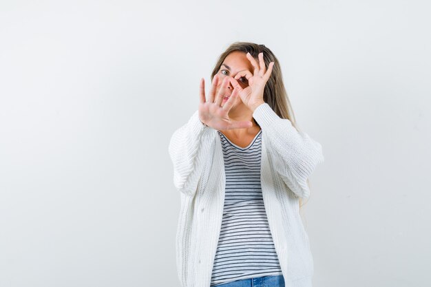 Jeune femme montrant un signe ok sur l'oeil avec un geste d'arrêt en t-shirt, veste et à la confiance. vue de face.