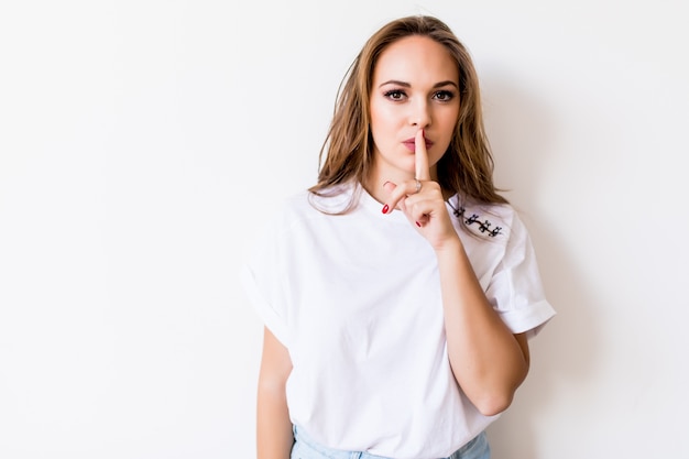 Jeune femme montrant signe de silence isolé sur blanc