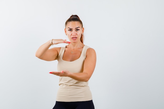 Jeune femme montrant le signe de la taille en maillot et à la perplexité. vue de face.