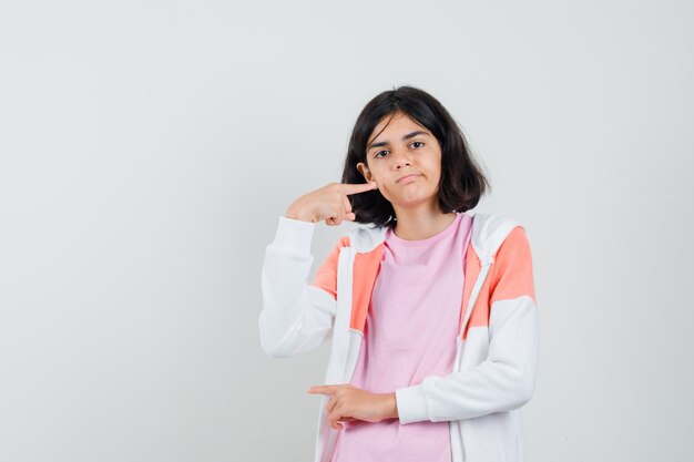 Jeune femme montrant la taille de quelque chose en veste, chemise rose et à l'air assuré.