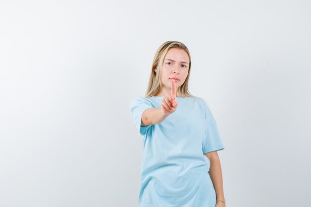 Jeune femme montrant tenir une minute en t-shirt et à la vue sérieuse, de face.