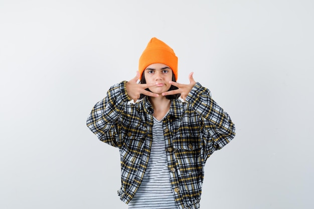 Jeune femme montrant trois doigts en chapeau orange et chemise à carreaux et à la malheureuse