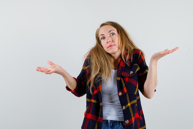 Photo gratuite la jeune femme montre qu'elle ne sait rien en ouvrant de larges mains sur fond blanc