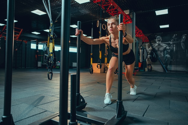 Jeune femme musclée pratiquant dans la salle de gym