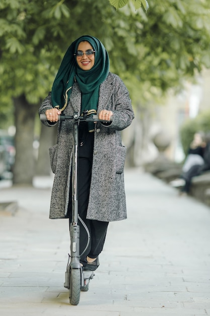 Photo gratuite jeune femme musulmane conduisant un scooter dans une rue