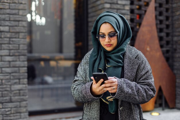 Jeune femme musulmane regardant dans un smartphone