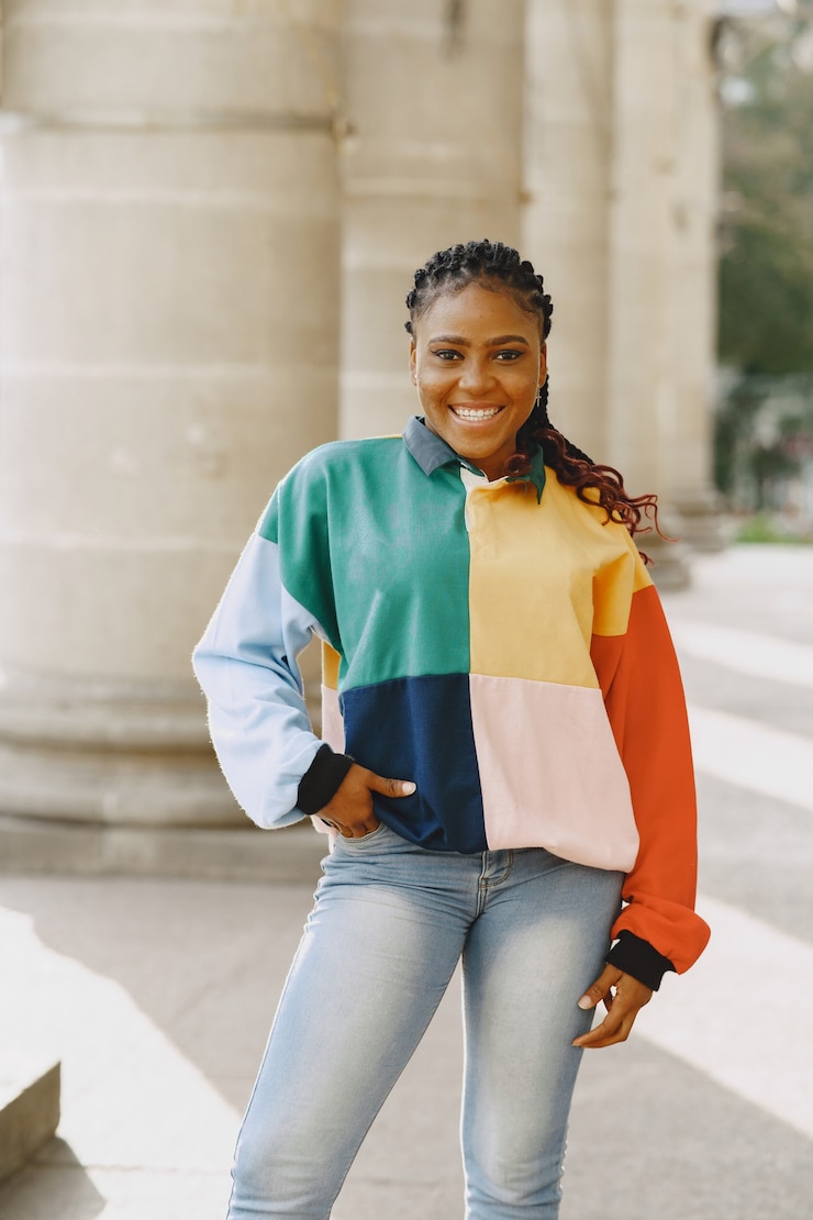 Photo gratuit jeune femme noire avec une coiffure afro souriant dans la ville urbaine. fille mixte dans un pull coloré.