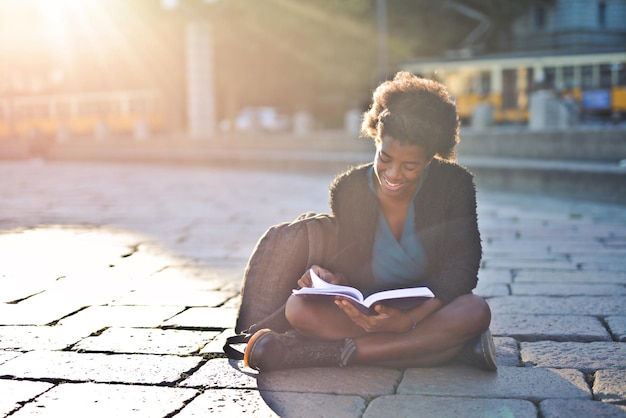 jeune femme noire dans la rue lit un livre