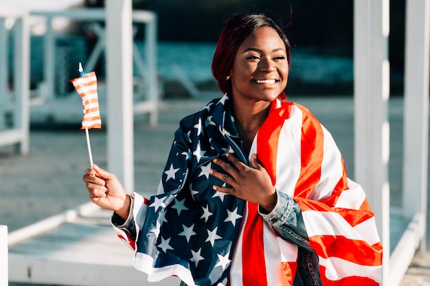 Jeune femme noire souriante avec des drapeaux des États-Unis