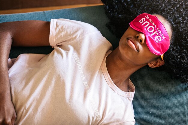 Jeune femme noire utilisant un masque pour les yeux pour dormir