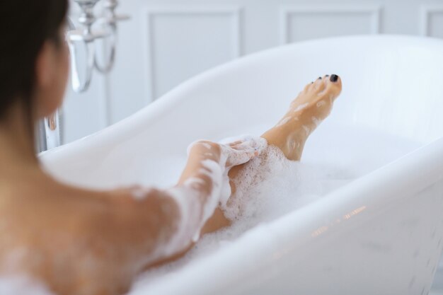 Jeune femme nue prenant un bain mousseux relaxant
