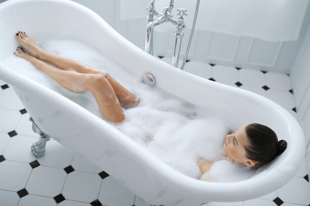 Jeune femme nue prenant un bain mousseux relaxant