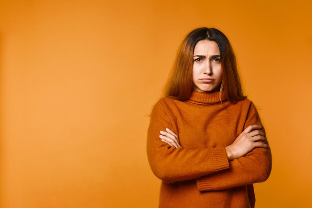 Jeune femme a offensé le regard et croisé les mains debout