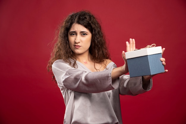 Jeune femme offrant une boîte cadeau bleue.