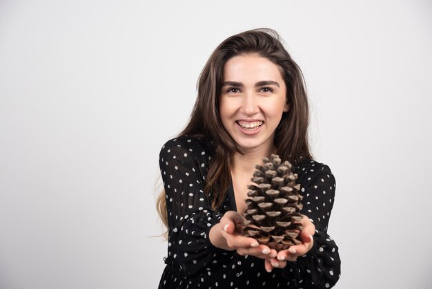 Jeune femme offrant une grosse pomme de pin