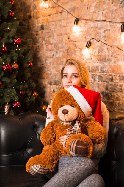 Jeune femme avec un ours en peluche portant un chapeau de Noël