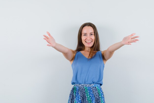 Jeune femme ouvrant les bras pour un câlin en maillot, jupe et à la joyeuse. vue de face.