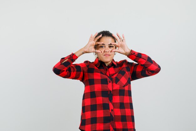 Jeune femme ouvrant les yeux avec les doigts en chemise à carreaux et à la fatigue