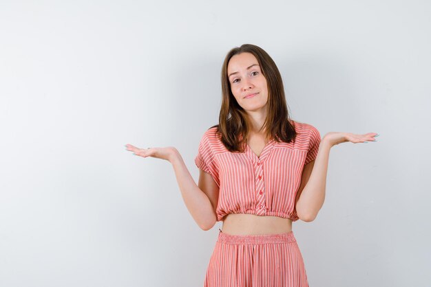 La jeune femme ouvre grand ses mains sur fond blanc