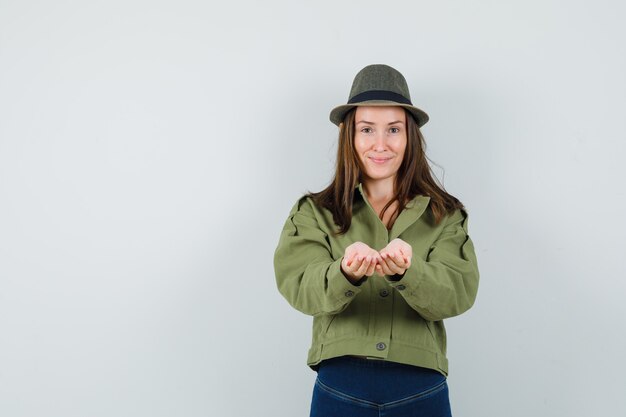 Jeune femme en pantalon veste hat étirement des mains en coupe et à la douceur
