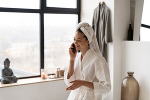 Photo gratuite jeune femme parlant au téléphone avant de prendre un bain