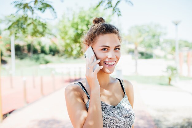 Jeune femme parlant au téléphone mobile dans la rue