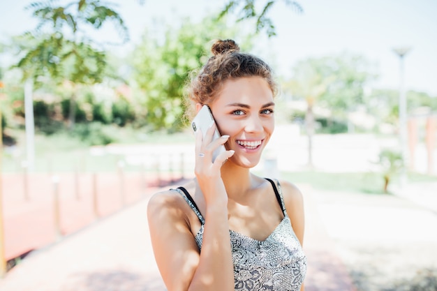 Jeune femme parlant au téléphone mobile dans la rue