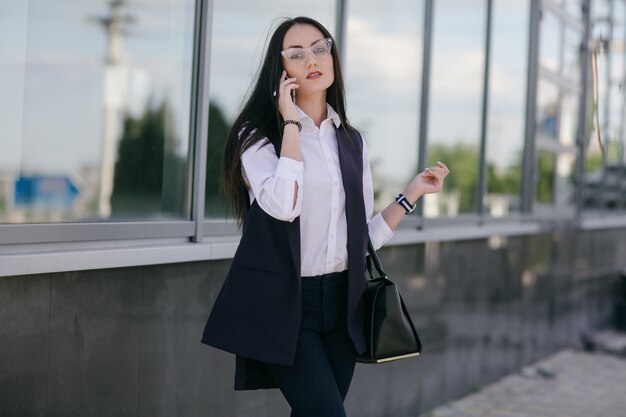 Jeune femme parlant sur un téléphone avec un sac noir