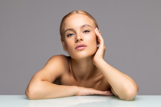 Jeune femme avec la peau de beauté sur le gris