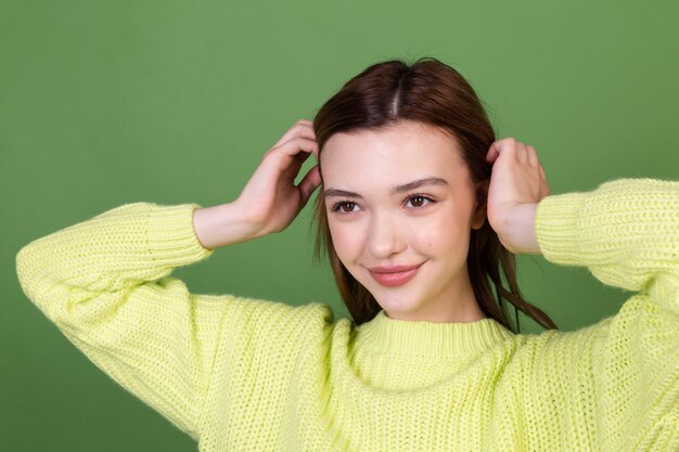 Jeune femme avec une peau naturelle parfaite et propre et maquillage brun grandes lèvres sur mur vert heureux sourire joyeux positif posant en mouvement