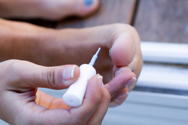 Jeune femme peignant ses ongles à la maison