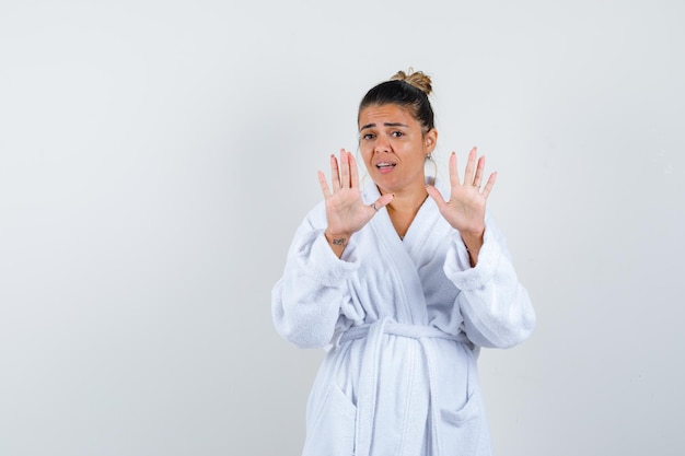 Jeune femme en peignoir montrant des panneaux d'arrêt et à la peur