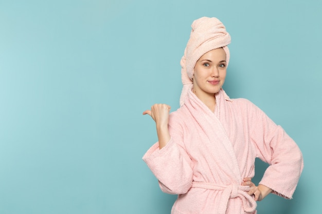 Photo gratuite jeune femme en peignoir rose après la douche posant juste sur le bleu