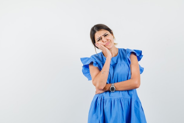 Jeune femme penchée joue sur la paume levée en robe bleue et à la sombre