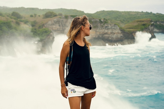 Une jeune femme photographe voyageuse avec un appareil photo au bord d'une falaise prend des photos de la nature
