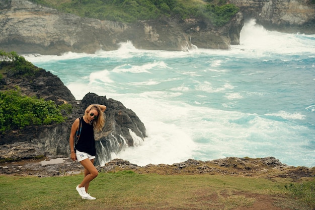 Une jeune femme photographe voyageuse avec un appareil photo au bord d'une falaise prend des photos de la nature