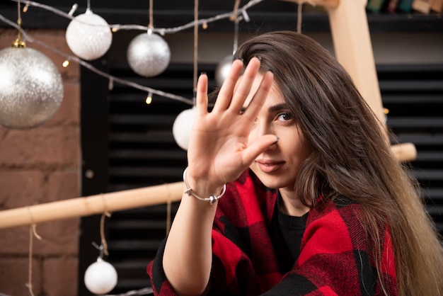 Jeune femme en plaid à carreaux posant près des boules de Noël.