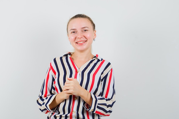 Jeune femme pliant ses mains en chemisier rayé et à la heureux