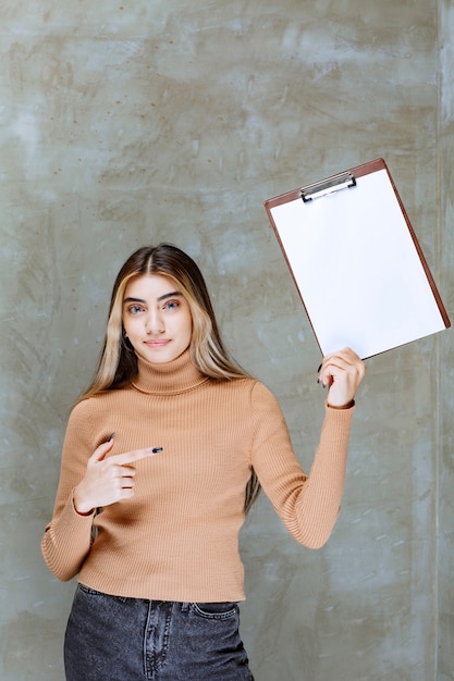 Jeune femme pointant sur un bloc-notes vide sur une pierre