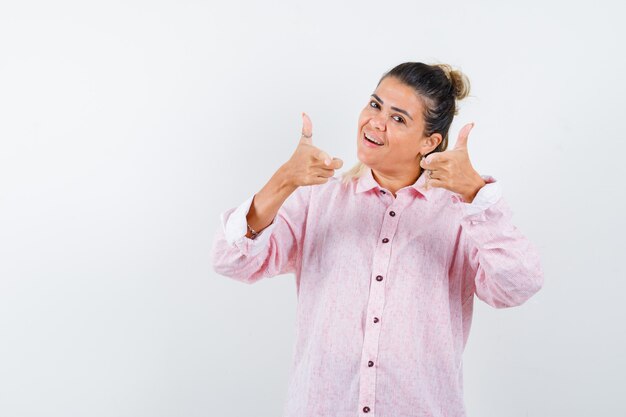 Jeune femme pointant la caméra en chemise rose et à la confiance