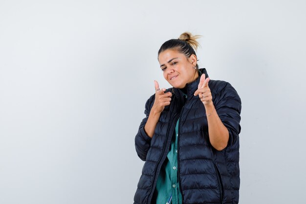 Jeune femme pointant en chemise, doudoune et à la gaieté. vue de face.