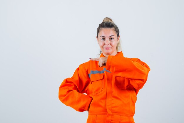 Jeune femme pointant sur le côté droit en vue de face uniforme de travailleur.