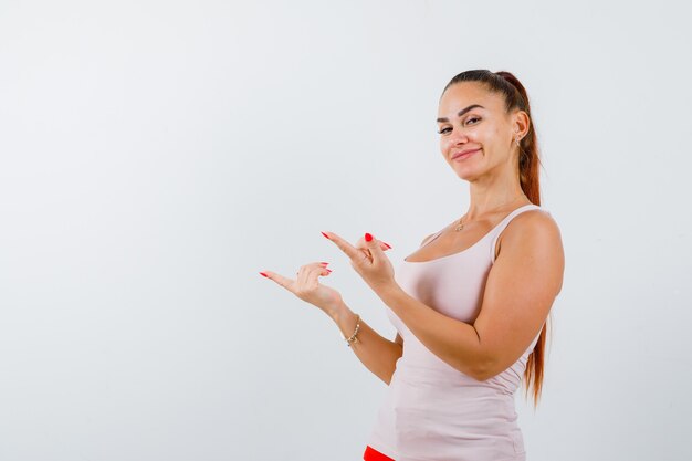 Jeune femme pointant de côté en maillot et à la confiance, vue de face.