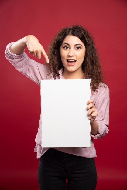 Jeune femme pointant sur une toile vide.