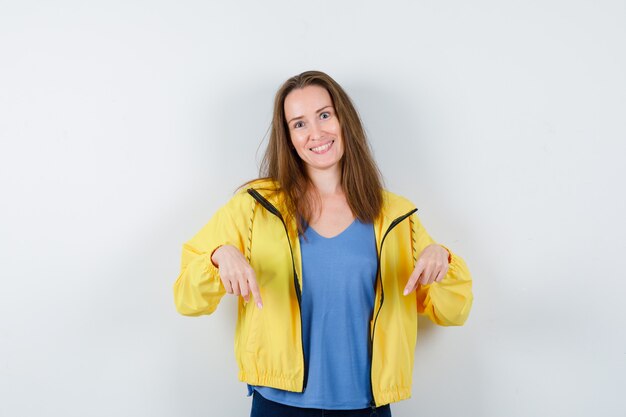 Jeune femme pointant vers le bas en t-shirt et à l'espoir, vue de face.